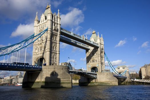 Wide daytime shot of Tower Bridge, London, UK, with a blue sky and white clouds