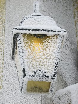 Frost covered lantern with yellow light glowing.