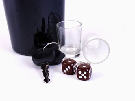 A black bottle with empty shotglasses, dice, and a pair of car keys. Drunk driving, is it worth the gamble? Over a white background.