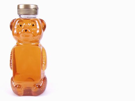 A bear shaped container of honey, off center with room for text on bear bottle and background. Over a white background.