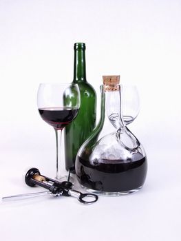 A caraffe of red wine chilled with ice. A glass of red, green bottle, and corkscrew sit with it.