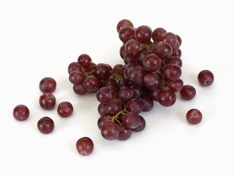 A bunch of red seedless grapes over a white background.