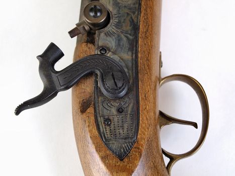 An antique black powder pistol in closeup view of hammer and trigger. Over a white background.