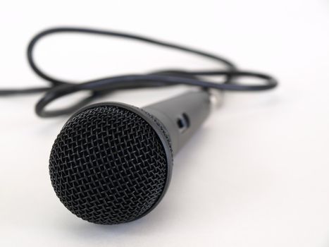 Studio microphone isolated on a white background with cord trailing off to the side.