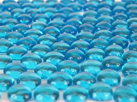 Blue glass beads taken in side shot, white highlights make eyes on faces.