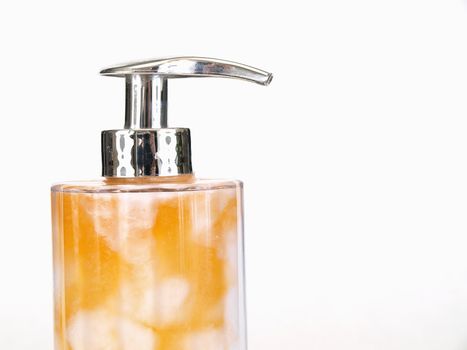 A soap pump with orange and white soap mixed inside. Over a white background.