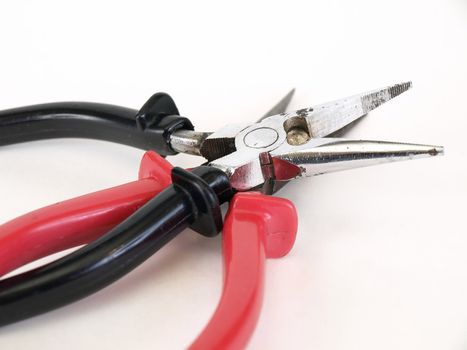 Two pair of needle nose pliers, red and black handled, open over a white background.