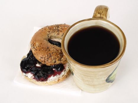A bagel with cream cheese and jelly, and a mug of hot beverage, over a white background.