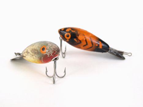 Two fishing lures with treble hooks over a white background.