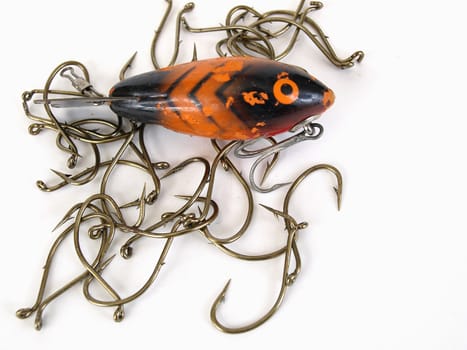 An orange fish shaped lure and fishing hooks over a white background
