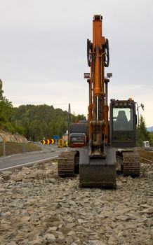 Excavator in evening light in front of road work.