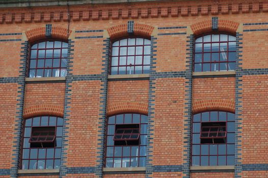 Six old fashioned windows on the side of a large red bricked building over looking the Regent's Canal in Camden Town.