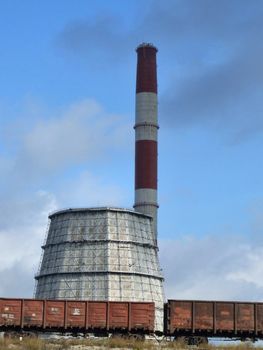 Industrial factory and cargo train. Chimney and a cooling tower.