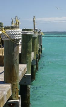 Sidelong view of a wooden jetty/ pier into turquoise ocean waters in the Bahamas