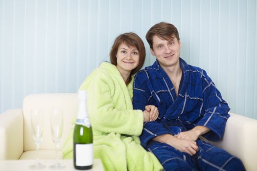 Young happy couple with sparkling wine on sofa