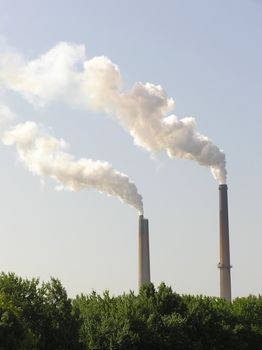 Industry pollution hidden behind green trees