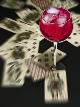 wineglass with the red wine on the table with heap of plaing cards