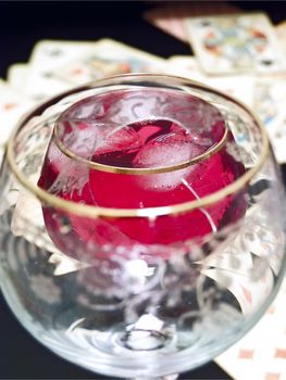 Wineglass with the red and plaing cards on the table tgrough broken glass