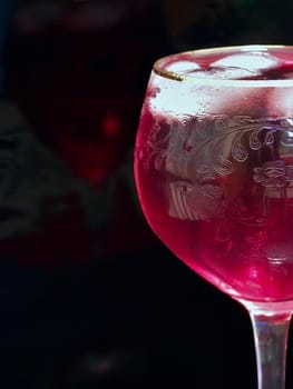 Half of wineglass full of red wine with ice