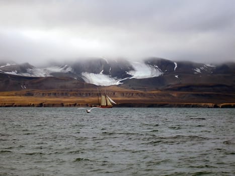 yacht against the coastline with mountains and clouds 