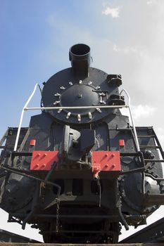 old black locomotive on background blue sky