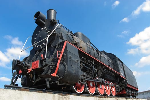 old black locomotive on background blue sky