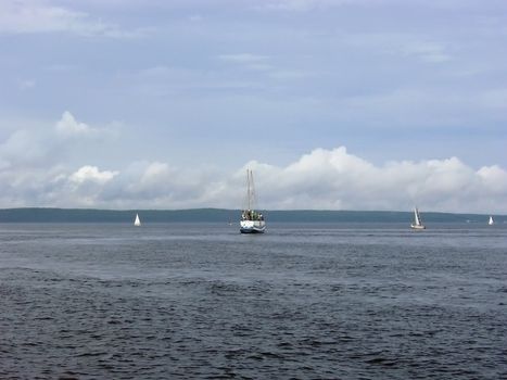 yachts against the coastline with the clouds