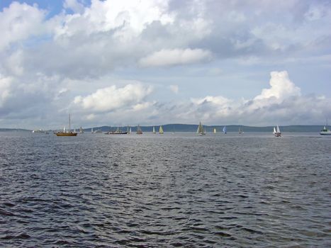 yachts against the coastline with the clouds