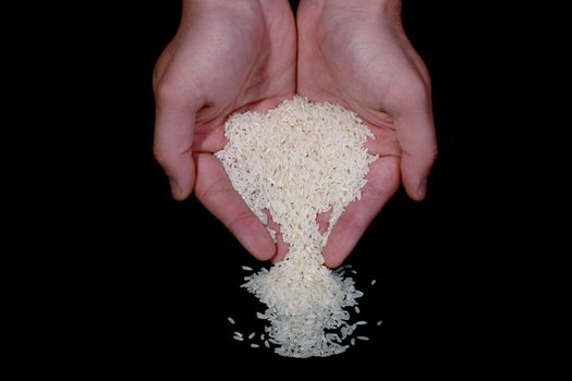 Man's hands pouring out rice on a black background.