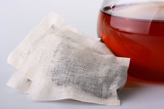 Tea tea leaves in bags from a material, nearby a teapot for tea leaves.