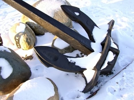 Winter iron anchor with the stones and snow