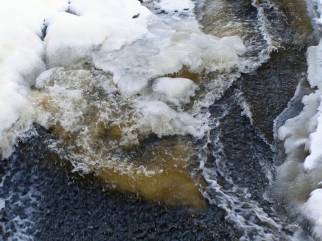 stream of water run through the snow and ice