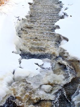 The stream of water run through the snow 