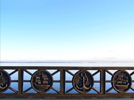 Tranquil water skyline with the blue sky and metal decorated barrier
