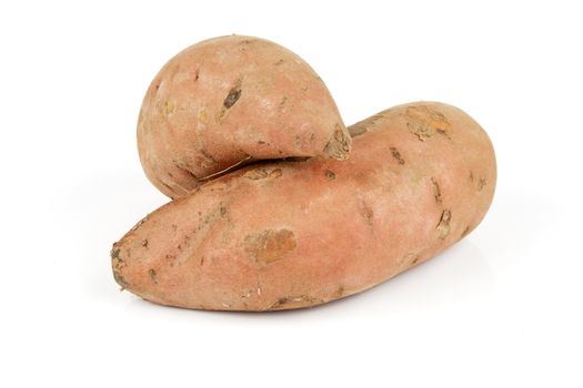 Two raw unpeeled sweet potatoes on a reflective white background