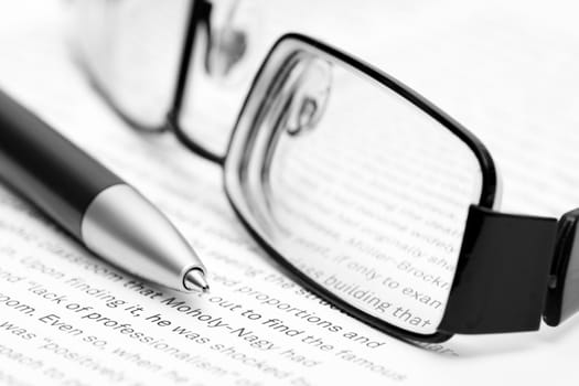 Open book with eyeglasses and pen in black and white