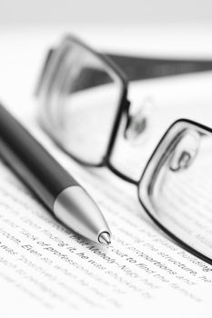 Open book with eyeglasses and pen in black and white