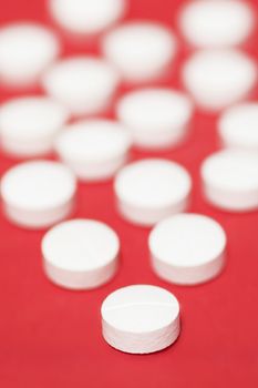 White Pills Over Red Background, Close-Up Shot, Focus On Front