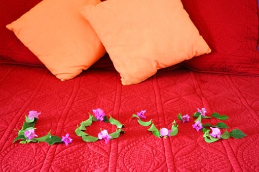 Love spelled out with flowers on bed