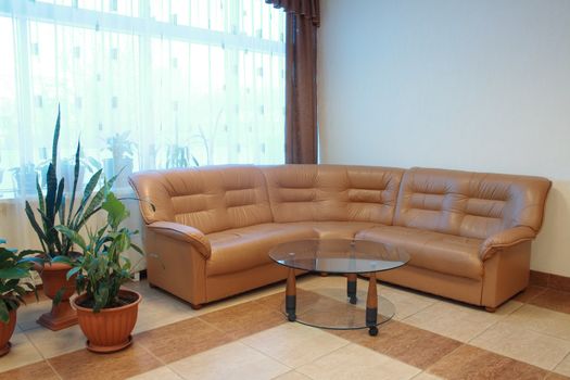 Nice home interior with brown leather sofa and round glass table