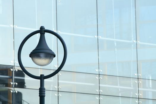 Modern street lamp on glass building wall background with copy space