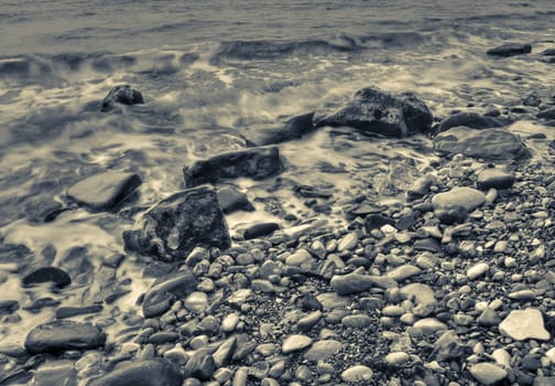 Duotone shot of stones at sea beach