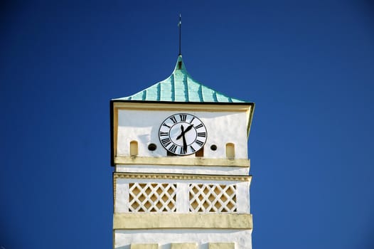 white clock tower and blue ski background, horizontally framed shot