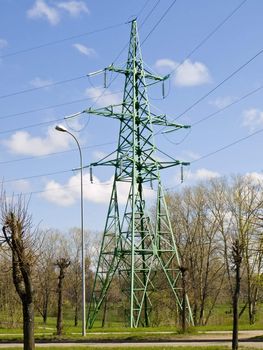 Single electricity tower in trees against the blue sky