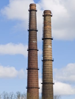 two chimneys against the blue sky and clouds
