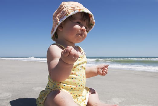 A baby eats sand during her first trip to the beach.