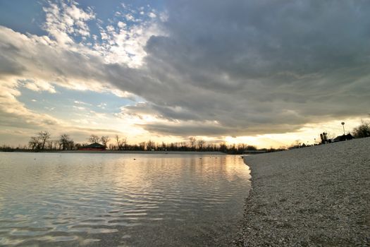 Cloud, lake and pebble coast sunset