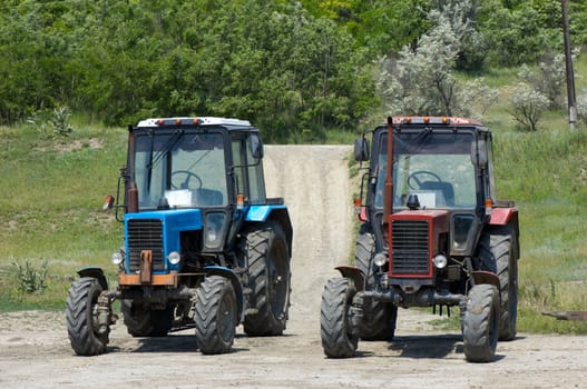 two dusty wheeled tractors at countryside, ready to work