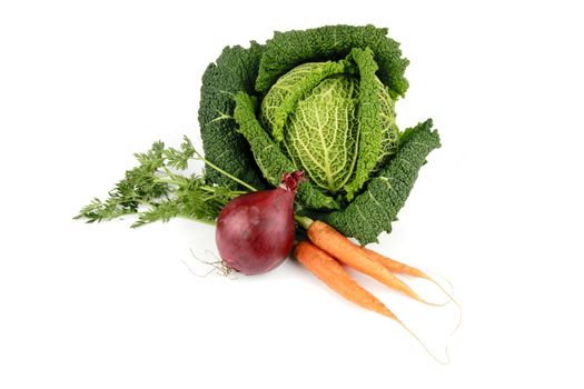 Single green raw cabbage with a single red onion and a bunch of carrots on a reflective white background