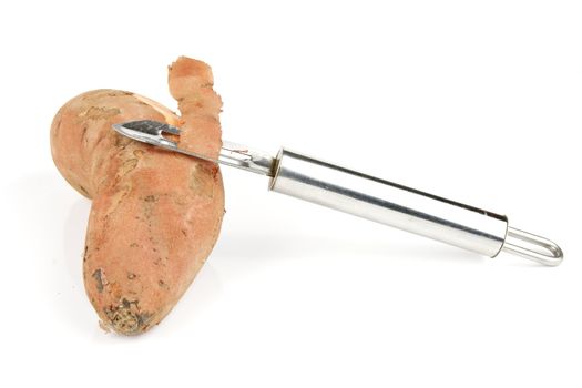 Sweet Potato cut in half with a silver potato peeler on a reflective white background